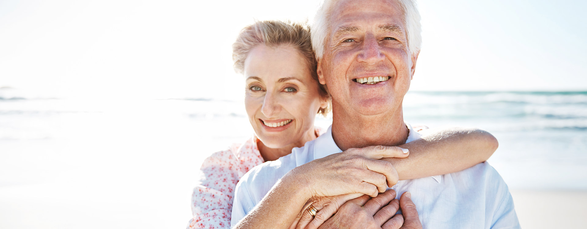 Frau umarmt Mann am Strand